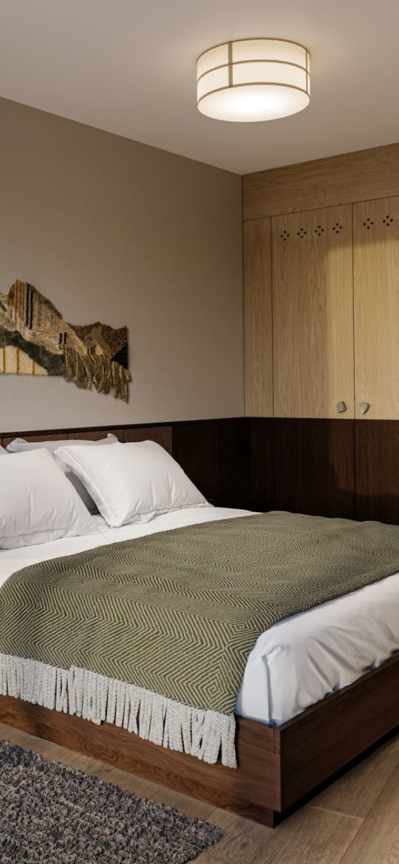 Im Schlafzimmer gibt es ein großes Bett mit weißen Kissen. Holzschränke und ein Teppich liegen auf dem Boden.
