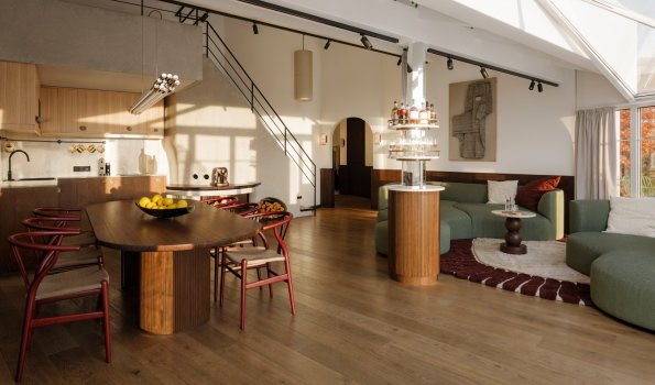Moderne Wohnküche mit viel Licht in einem Haus In einem hellen Raum stehen ein Esstisch und eine Couch. Tageslicht fällt durch große Fenster auf den Boden.