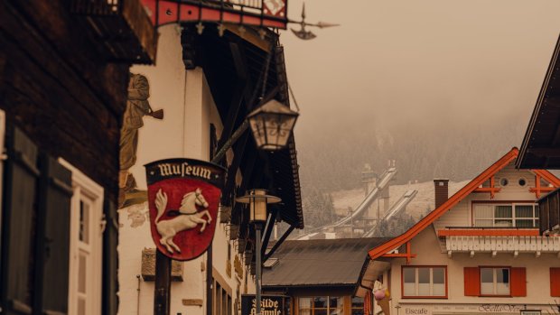 In Garmisch-Partenkirchen sind alte Gebäude und Geschäfte zu sehen. Die Wolken hängen tief über den Bergen.