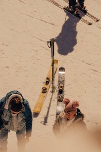 Menschen stehen auf der Piste und bereiten sich zum Skifahren vor. Die Sonne scheint und die Schneedecke ist hell.