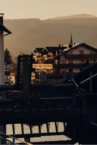 Das Dorf liegt in den Bergen. Sonnenstrahlen scheinen auf die Gebäude. Der Fluss spiegelt die Umgebung wider.