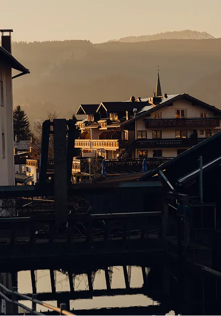 Das Dorf liegt in den Bergen. Sonnenstrahlen scheinen auf die Gebäude. Der Fluss spiegelt die Umgebung wider.