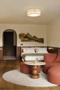 Das Zimmer zeigt ein Bett, eine Sitzecke und einen Tisch. Es ist hell und hat einen modernen Stil, warm und freundlich.