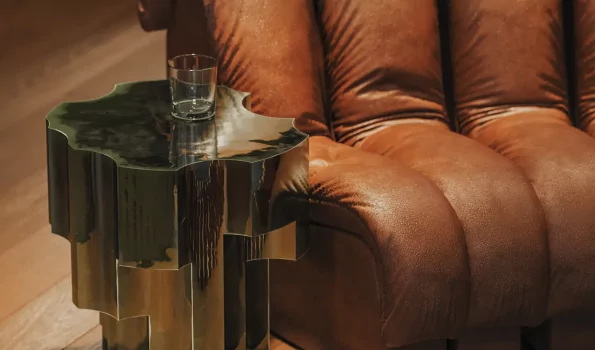 Ein braunes Sofa und ein Tisch in einem Raum In einem Raum steht ein braunes Sofa neben einem Tisch. Auf dem Tisch steht ein Glas. Es ist Abend und es gibt warmes Licht.