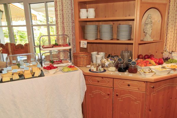Frühstücksbuffet in einer Ferienunterkunft Es gibt viele Speisen auf dem Buffet. Käse, Obst und Brot stehen bereit. Die Sonne scheint ins Zimmer.