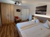 Zimmer mit zwei Betten in einer Unterkunft Das Zimmer hat zwei Betten, einen Schrank und einen Stuhl. Es ist hell und hat einen Zugang zur Tür.
