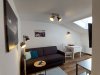 Gemütlicher Raum mit Sofa und Tisch In einem kleinen Raum steht ein Sofa und ein Tisch. Ein Fenster lässt Licht hereinkommen und die Wände sind hell.