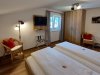 Ein Zimmer mit zwei Betten und Fernseher In einem Raum stehen zwei Betten. Eine Wand hat einen Fernseher. Es gibt Stühle und einen Schrank. Das Fenster ist offen.