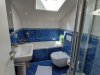 Badezimmer mit blauen Fliesen und Tageslicht Das Badezimmer hat eine Badewanne, eine Dusche und ein Fenster für Tageslicht. Es gibt auch Pflanzen und Handtücher.