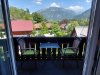Balkon mit Blick auf die Berge und die Landschaft Der Balkon hat zwei Stühle und einen Tisch. Im Hintergrund sind Berge und viele Bäume zu sehen. Es ist sonnig.