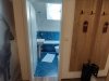 Badezimmer mit blauen Fliesen und Eingang Der Raum zeigt ein Badezimmer mit blauen Fliesen und einem Zugang. Es gibt eine Toilette, ein Waschbecken und einen Spiegel.