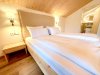 Modernes Zimmer in einer Unterkunft mit Holzdetails In einem Zimmer befinden sich ein Bett und ein Nachttisch. Das Badezimmer ist in der Nähe. Es gibt viel Licht und Holz.