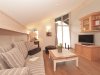 Wohnzimmer mit Sofa und Fernseher in einer Wohnung Das Wohnzimmer zeigt ein Sofa, einen Tisch und einen Fernseher. Licht kommt durch große Fenster.