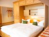 Schlafzimmer mit Doppelbett und Möbel aus Holz In einem Raum steht ein Doppelbett mit weißen Bettdecken. Es gibt Holzregale und eine warme Beleuchtung.