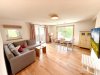 Wohnzimmer in einer modernen Wohnung mit Möbeln Eine helle und offene Wohnung mit einem Wohnzimmer, einem Essbereich und Fenstern. Die Einrichtung ist einfach und modern.