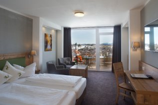 Einblick in eines der Zimmer im Nesselwanger Hof in Nesselwang mit Blick auf das Doppelbett und den Balkon