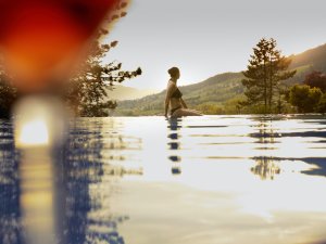 Eine Frau genießt die Aussicht auf das Bergpanorama im Außenpool des Hotel Prinz-Luitpold-Bads in Bad Hindelang