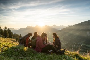 Eine Gruppe von Gästen macht ein Picknick im Sonnenschein bei einer Wanderung in den Bergen in der Umgebung des Panoramahotels Oberjoch
