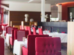 Einblick in den Speiseraum mit roten Stühlen und gedeckten Tischen im Rosenalp  Gesundheitsresort und Spa in Oberstaufen