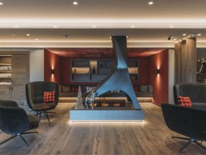 Lounge in der Rosenalp Gesundheitsresort und Spa in Oberstaufen mit Kamin, gemütlichen Sesseln in schwarz und farbliche Details in rot