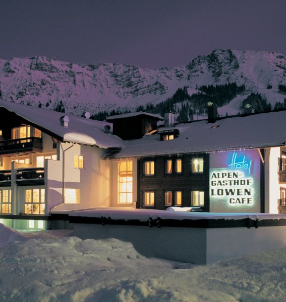 Die Außenansicht des verschneiten und hell beleuchteten Hotels Alpengasthof Loewen in Oberjoch im Winter