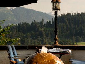 Ein Tisch und Stühle auf der Terrasse im Wellnesshotel Mittelburg in Oy-Mittelburg mit Blick auf die Berge im Sommer