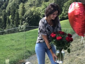 Eine Frau, die Gast im Hotel Bergkristall - Mein Resort im Allgäu in Oberstaufen ist, erhält einen Strauß rote Rosen und einen Herzluftballon.