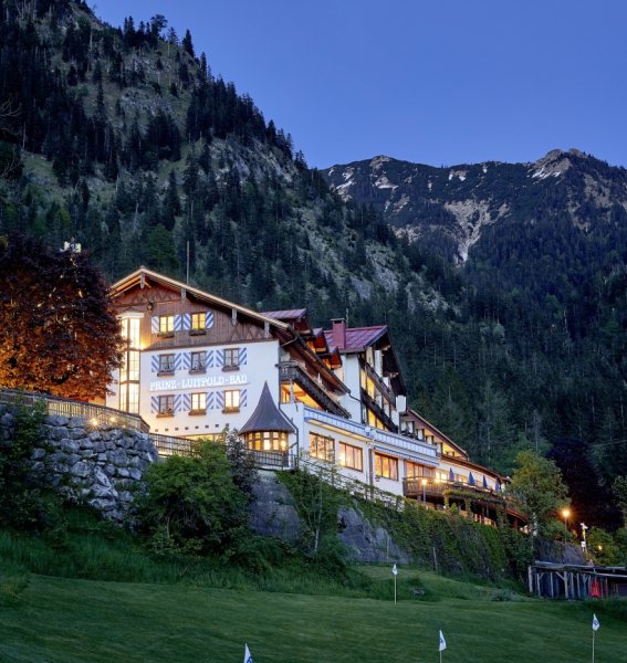 Außenansicht des Hotel Prinz-Luitpold-Bad in Bad Hindelang an einem schönen stimmungsvollen Sommer-Abend mit Blick auf die umliegenden Berge und Landschaft