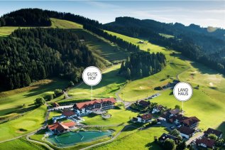 Die Außenansicht des Haubers Naturresort in Oberstaufen umgeben von Wiesen und Bergen im Sommer.