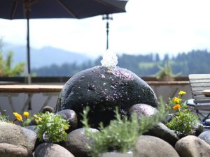 Ein Springbrunnen auf dem Balkon mit Ausblick auf das Bergpanorama im Wellnesshotel Mittelburg in Oy-Mittelburg