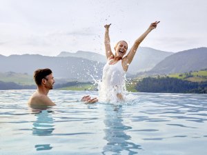 Ein Paar gemeinsam im Außenpool des Bergkristall - Mein Resort im Allgäu in Oberstaufen