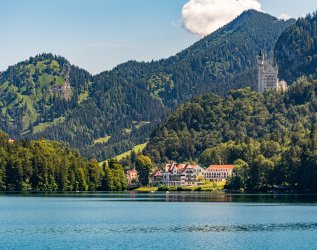 Sommerlicher Blick auf den Alpsee im Hintergrund mit dem Schloss Neuschwanstein und dem Hotel AMERON in Schwangau.