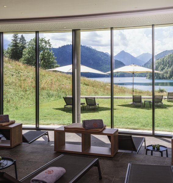 Blick aus den Panoramafenstern des Wellnessbereichs auf den Alpsee im Sommer des AMERON in Schwangau.