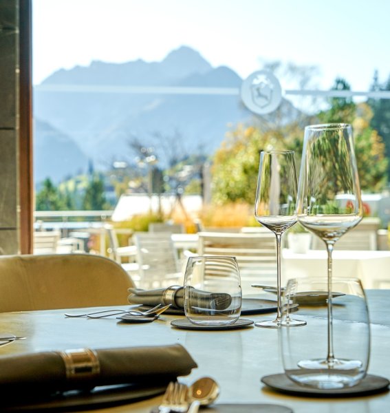 Ein gedeckter Tisch mit Ausblick auf die Berge im Restaurant im Travel Charme Ifen Hotel im Kleinwalsertal.