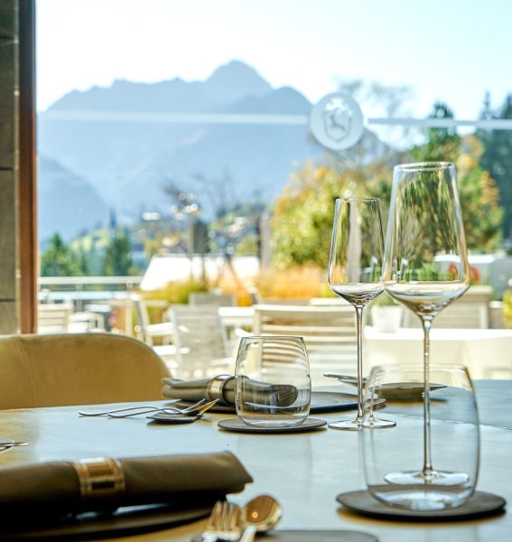 Ein gedeckter Tisch mit Ausblick auf die Berge im Restaurant im Travel Charme Ifen Hotel im Kleinwalsertal.