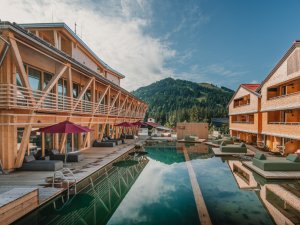 Außenansicht des Hotels HUBERTUS Mountain Refugio Allgäu in Balderschwang mit Blick auf den Natur-Badesees und der spektakulären Aussicht