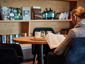 Eine Frau, die Gast im Bergkristall - Mein Resort im Allgäu in Oberstaufen ist, liest ein Buch und trinkt Tee.