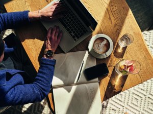 Ein Gast trinkt einen Kaffee und arbeitet an einem Tisch im A-Rosa Ifen Hotel Kleinwalsertal