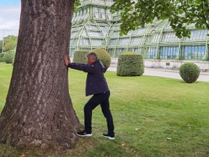 Ein Gast lehnt sich gegen einen dicken Baumstamm im Biohotel Mattlihüs in Bad Hindelang