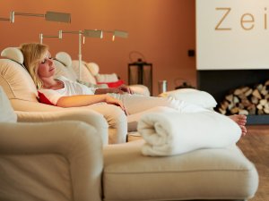 Eine Frau genießt eine Auszeit im Ruheraum im Schüle's Gesundheitsresort und SPA in Oberstdorf