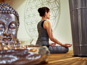 Eine Frau, die Gast im Hotel König Ludwig in Schwangau ist, entspannt sich bei einer Yogaübung.