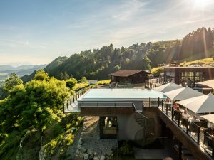 Außenansicht vom Hotel Bergkristall - Mein Resort im Allgäu in Oberstaufen mit Blick auf den Infinitypool und atemberaubende die Landschaft