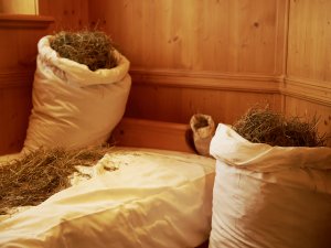 Ein Bett mit Heusäcken für eine Wellnessbehandlung im Schüle's  Gesundheitsresort und SPA in Oberstdorf