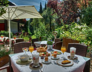 Außenansicht des DIANA Naturpark Hotels in Oberstaufen im Sommer mit Blick auf die Terrasse mit einem ansprechend gedecktem Tisch voller Frühstücks-Leckereien