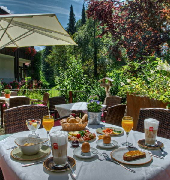 Außenansicht des DIANA Naturpark Hotels in Oberstaufen im Sommer mit Blick auf die Terrasse mit einem ansprechend gedecktem Tisch voller Frühstücks-Leckereien