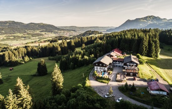 Außenansicht des Berghotels Sonnenklause in Sonthofen im Sommer mit Blick von einer Drohne im Himmel auf das Hotelgebäude und die umliegende schöne Landschaft