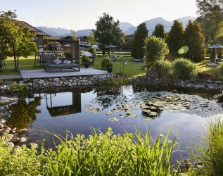 Außenansicht vom Hotel Rosenstock in Fischen mit Blick auf den Teich und großen Garten des Hotels