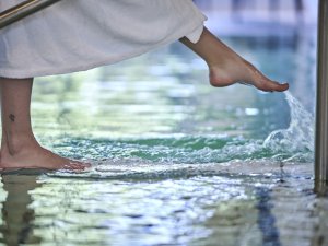 Eine Frau läuft durch das Wasser des Innenpools im Hotel Bannwaldsee in Halblech