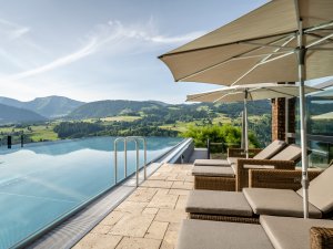 Blick auf den Außenpool und die Liegestühle mit Sonnenschirmen im Bergkristall Mein Resort im Allgäu in Oberstaufen