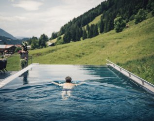 Blick auf den Außenpool und die umliegende Natur rund um das Hotel Torghele's Wald & Fluh in Balderschwang